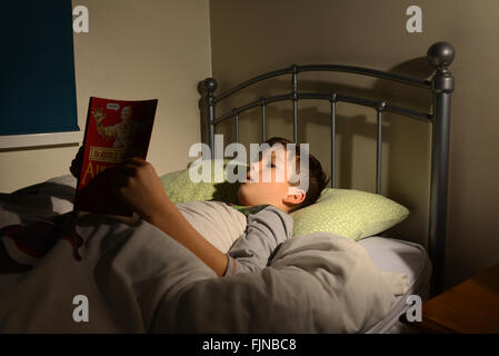 Ragazzo lettura a letto bambino la lettura di un libro che giace nel suo letto, Bedtime Story, di coricarsi leggere Foto Stock