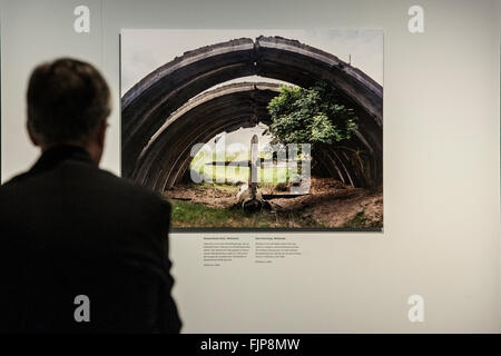 Berlino, Germania. 03 Mar, 2016. Un uomo guarda una fotografia dei resti di un vecchio aereo da combattimento in Wittstock dal fotografo olandese Martin Roemers nel Museo Storico Tedesco a Berlino, Germania, 03 marzo 2016. Roemers mostra oltre 70 di grande formato a colori per le foto al Museo Storico Tedesco sotto il titolo "reliquie della Guerra Fredda." Questi mostrano l'architettura e topografico rimane del vecchio conflitto est-ovest. La foto può essere visto dal 04 marzo fino al 15 agosto 2016. Foto: PAOLO ZINKEN/dpa/Alamy Live News Foto Stock