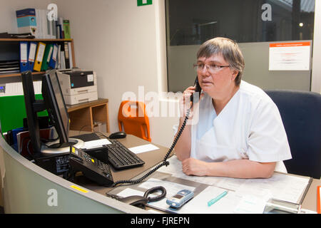 L'infermiera presso il banco della reception in ospedale Foto Stock