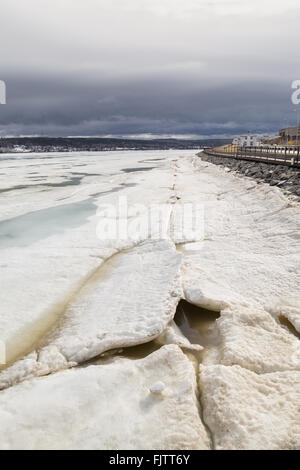 Linea di rotto il ghiaccio galleggiante sul St Larence fiume in Gaspe, Quebec, Canada. Il cielo è grigio e nuvoloso. Foto Stock