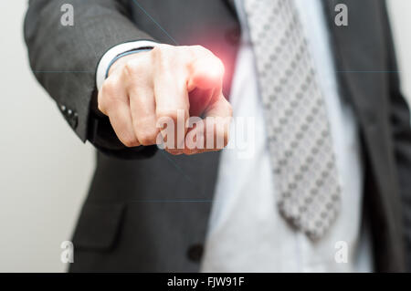 Uomo d affari con il dito puntato a qualcosa o toccando uno schermo touch screen con candelette effetto tattile Foto Stock