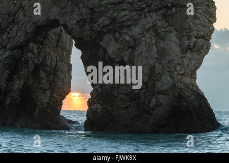 Il Rising Sun su una mattina inverni visto attraverso l'arco calcareo di Durdle porta sul Jurassic Coast di Dorset, Regno Unito Foto Stock