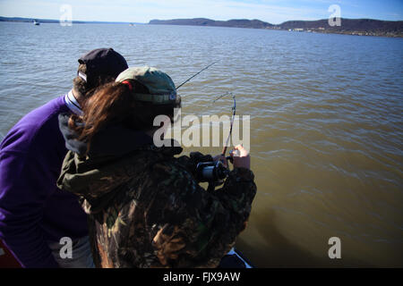 Ragazza giovane la bobinatura in un pesce fuori dalla parte laterale di una barca sul fiume Hudson, New York. Foto Stock