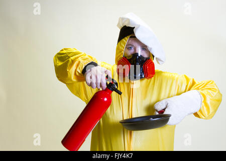 Donna matura in giallo hazmat suit e chef hat holding di pan e di estintore. Foto Stock