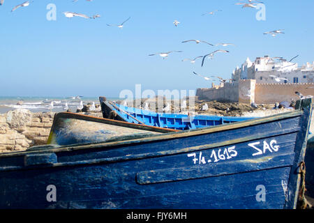 Barche da pesca ormeggiate a Essaouira in Marocco con il vecchio forte portoghese in background. Foto Stock