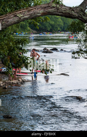 La gente godendo di un weekend sull'acqua con tubi e paddleboarding sul francese ampio fiume in Asheviille, North Carolina. Foto Stock