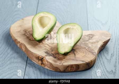 Due metà di avocado maturo sul bordo di taglio sopra il tavolo Foto Stock