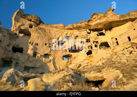 Parte della scogliera abitazione complesso di antiche chiese cristiane e case nel villaggio di Cavusin vicino a Goreme, Cappadocia, Turchia Foto Stock