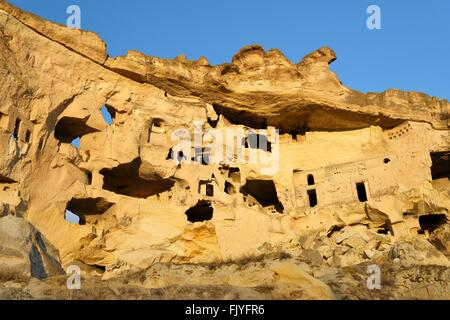 Parte della scogliera abitazione complesso di antiche chiese cristiane e case nel villaggio di Cavusin vicino a Goreme, Cappadocia, Turchia Foto Stock