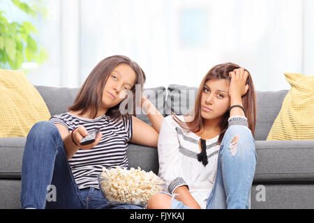 Annoiato teenage sorelle di guardare la TV e cambiare i canali isolati su sfondo bianco Foto Stock