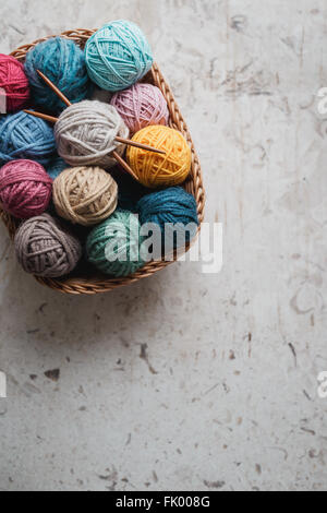 Aghi da maglia e sfere di filato in basket Foto Stock