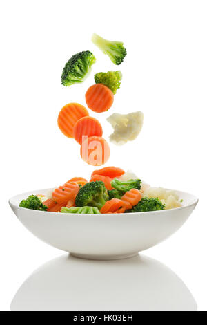 Verdure miste di cadere in una ciotola di insalata Foto Stock