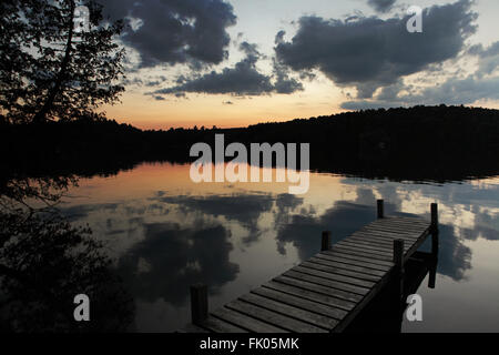 Il sole tramonta su un lago in western Vermont, USA. L'estate le nuvole sono riflesse nella perfettamente calmo lago Foto Stock