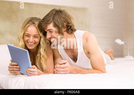 Carino coppia utilizzando tablet giacente a letto Foto Stock
