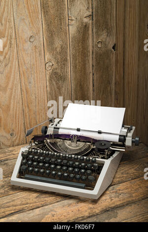 Macchina da scrivere di antiquariato con carta bianca pagina su un tavolo di legno. in stile vintage still life Foto Stock