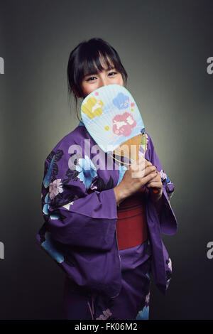 Bella donna giapponese sorridente dietro oriental ventola . Studio shot Foto Stock