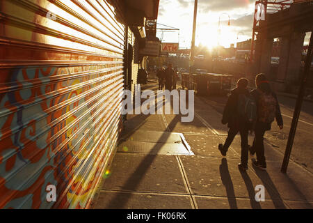 Due studenti a scuola a piedi a est nella Rising Sun giù Delancey Street sulla Lower East Side di Manhattan Foto Stock