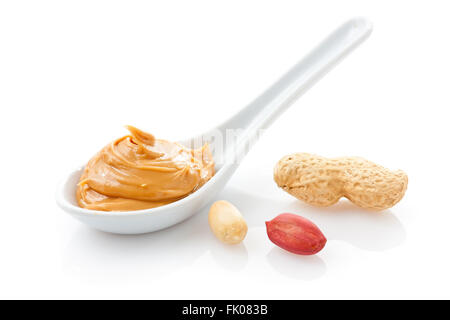 Crema di burro di arachidi in un cucchiaino di colore bianco con arachidi Foto Stock
