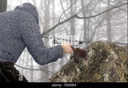 Valoroso cavaliere anonimo rimuove l'Excalibur magica spada nella roccia Foto Stock