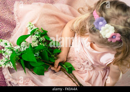 Bellissima ragazza con lunghi capelli biondi azienda fiori e indossando fatta in casa con archetto Foto Stock