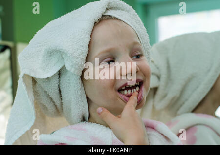 Bella ragazza in accappatoio con asciugamano in i suoi capelli che mostra i denti Foto Stock