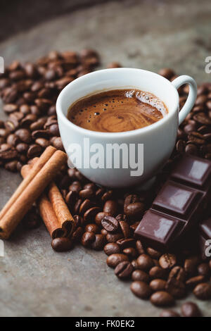 Tazza di caffè circondato da cioccolato, bastoncini di cannella e i chicchi di caffè Foto Stock