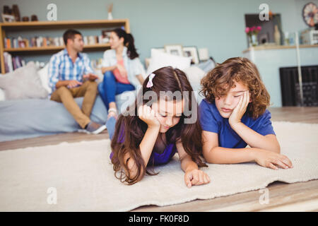 I bambini in appoggio sul tappeto mentre i genitori in background Foto Stock