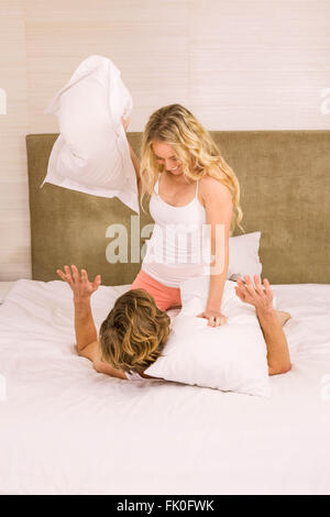 Giovane coppia che lotta con cuscino sul letto in camera da letto Foto stock  - Alamy