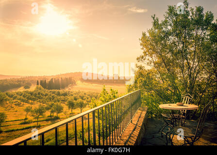 Luce solare su campo di olive in Toscana con una tabella su una terrazza in primo piano Foto Stock