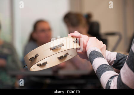 Un bambino disabile in un gruppo godendo di musicoterapia Foto Stock