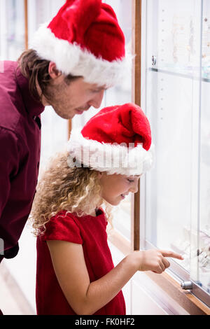 Padre e figlia in abito di Natale guardando il display di gioielli Foto Stock