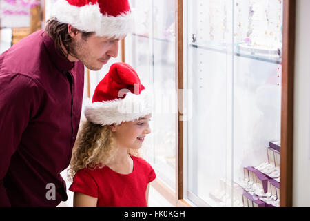 Padre e figlia in abito di Natale guardando il display di gioielli Foto Stock