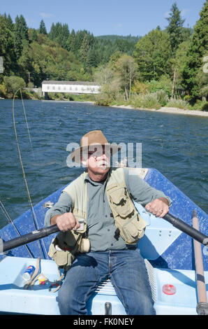 Un anziano pescatore righe deriva la sua barca su un bel giorno di estate in prossimità del Goodpasture ponte coperto, che abbraccia i Mckenzie Foto Stock