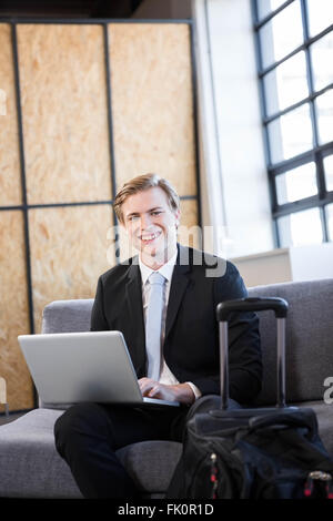 Happy businessman seduti sul divano e tramite computer portatile Foto Stock