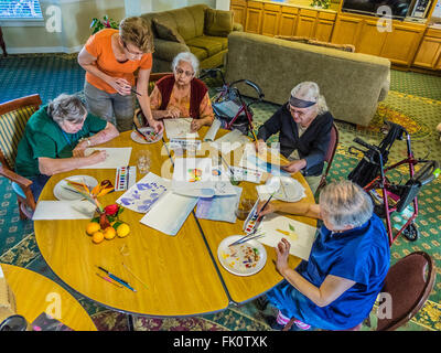 Un insegnante femminile aiuta i cittadini anziani vernice in un acquerello di classe per seniors a un senior centre di Santa Barbara in California. Foto Stock