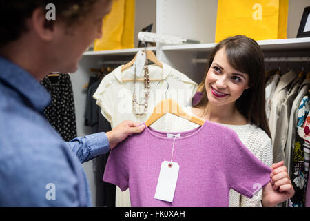 Giovane selezionando un abito mentre lo shopping per i vestiti Foto Stock