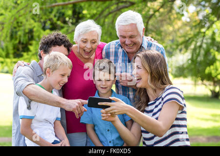 Famiglia sorridente utilizza lo smartphone Foto Stock