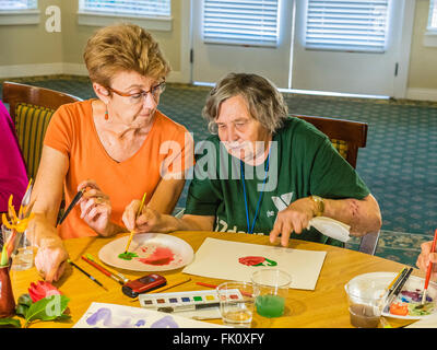 Una femmina la maestra insegna una femmina senior citizen di vernice in un acquerello di classe a un senior centre di Santa Barbara. Foto Stock