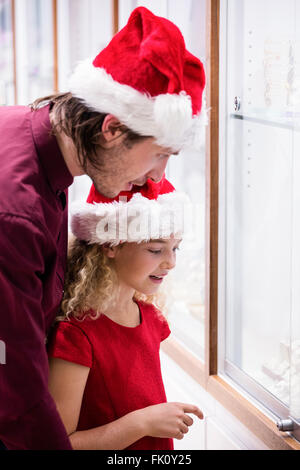 Padre e figlia in abito di Natale guardando il display di gioielli Foto Stock