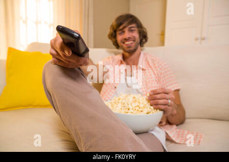 Uomo bello guardare la TV e mangiare pop corn Foto Stock