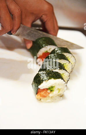 Lo Chef tagli Roll sushi su una lavagna bianca Foto Stock