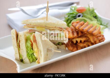 Appena sfornati club sandwich servito con patate fritte Foto Stock