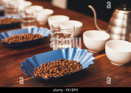 I chicchi di caffè e tazze in una riga la preparazione per la degustazione Foto Stock