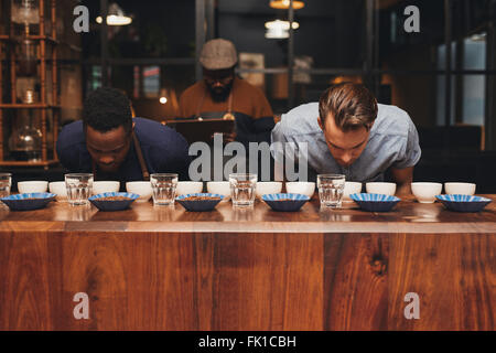 Righe di chicchi di caffè e tazze con baristi profumati aromi Foto Stock