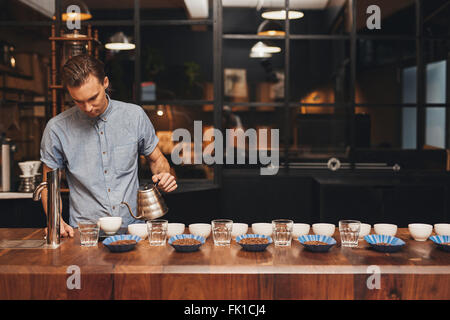 Barista preparazione di degustazione del caffè con righe di tazze e fagioli Foto Stock