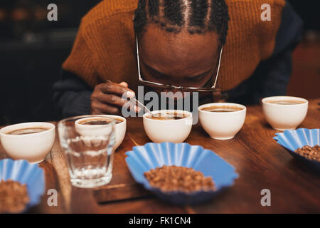 L'uomo africano Annusare il profumo del caffè a una degustazione Foto Stock