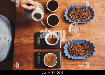 Barista versando acqua nella tazza di caffè macinato sulla scala Foto Stock