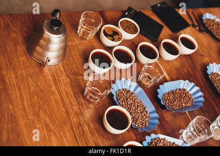 Tazze di caffè, fagioli e bollitore su tavola per la degustazione Foto Stock