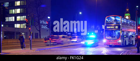 Auto ad alta velocità della polizia metropolitana luci blu lampeggianti che illuminano il cielo notturno autobus rosso di Londra di Westminster Bridge in attesa al semaforo Inghilterra Regno Unito Foto Stock