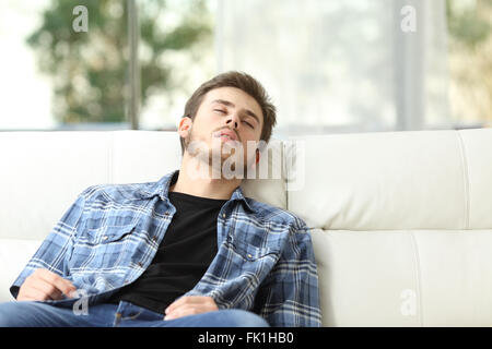 Vista frontale di un uomo stanco di dormire su un divano a casa Foto Stock